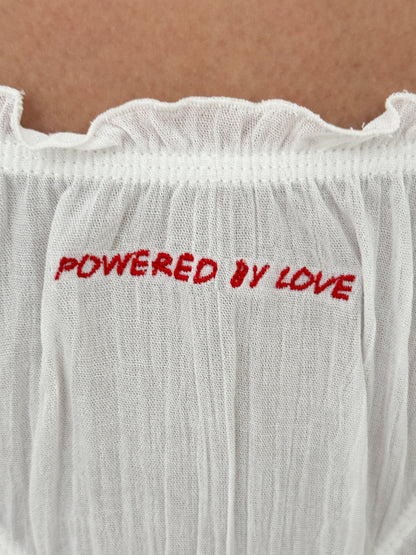 Біла танга з червоним написом POWERED BY LOVE, крупний план